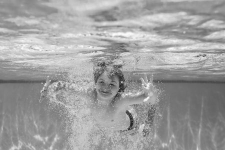 Underwater child in the swimming pool. Cute kid boy swimming in pool under water.の写真素材