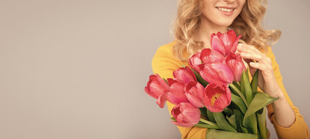 cropped smiling woman with tulips. lady hold flowers for spring holiday. girl with bouquetの写真素材