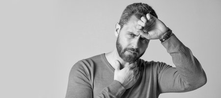 mature man with beard has heacache suffer from headahce on grey background, malaise. Man face...