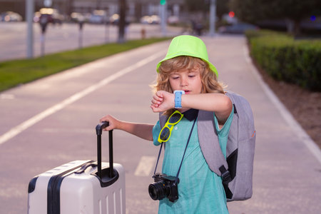 Child tourist with luggage travel bag travelling. Kid with suitcase walk on city street outdoor. Traveler tourist kid in casual clothes and hat hold suitcase.の写真素材