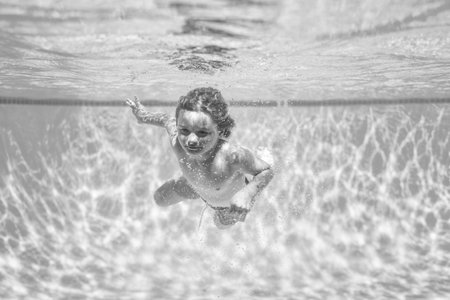 Underwater kids swims in pool, healthy child swimming and having fun under water.