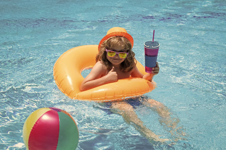 Kids swimming and playing in a pool. Child playing in swim pool. Summer fashion kids portrait. Vacation in a tropical resort. Swimwear for children. Summer rest and relaxation.の写真素材