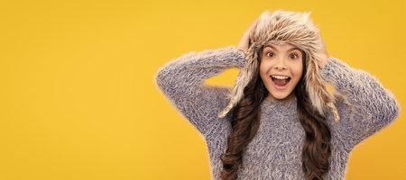 female fashion model. teen girl in knitwear on yellow background. Banner of child girl in winter hat, studio poster header with copy space.の写真素材
