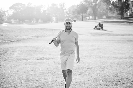 portrait of golfer in cap with golf club walk on green grass, golfing