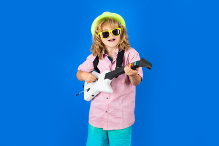 Cute child boy sings and plays on the electric guitar with bright emotions. Fashion American country...