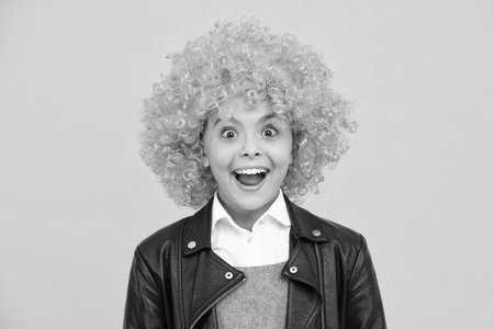 Girls birthday party. Funny kid in curly redhead wig. Time to have fun. Teen girl with orange hair, being a clown. Excited face, cheerful emotions of teenager girl.の写真素材