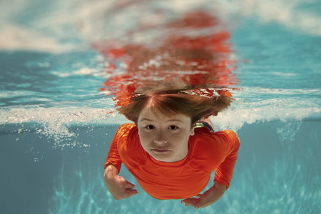 Kid boy swim underwater in sea. Kid swimming in pool under water. Active kid swimming, playing and diving, children water sport.の写真素材