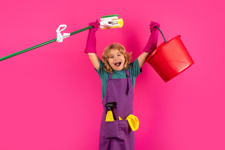Child doing housework. Studio portrait of child use duster and gloves for cleaning. Funny child mopping house. Cleaning accessory, cleaning supplies. Housekeeping and home cleaning.の写真素材