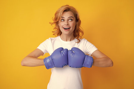 Funny woman in boxing gloves. Winning woman, success concept, isolated on yellow background.の写真素材