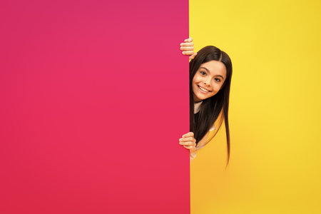 Teenage girl holds a blank for notification informing. Advertisement and sale. Markets and shops sales concept, blank board for copy space. Happy kids face, positive and smiling emotions.の写真素材