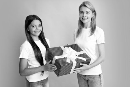 Young teen girl giving gift box to her mother on color background. Happy family. Mother and daughter with present gift.の写真素材