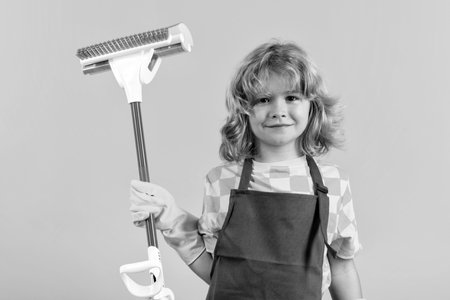 Child doing housework. Child use duster and gloves for cleaning. Funny child mopping house. Cleaning accessory, cleaning supplies. Housekeeping and home cleaning.の写真素材