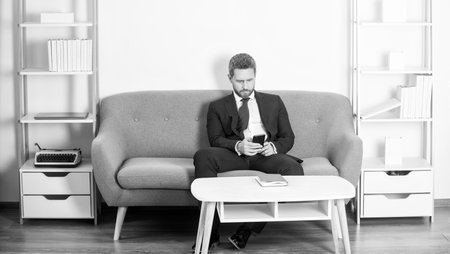 businessman sitting in office and chatting on phoneの写真素材