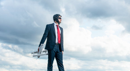 businessman in suit and pilot hat launch plane toy on sky background. inspirationの写真素材