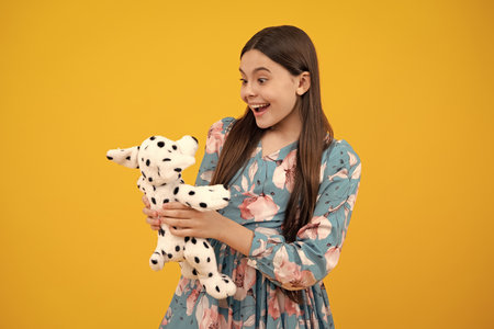 Teen girl child in casual wear holding plush toy isolated on yellow background, happy childhood.の写真素材