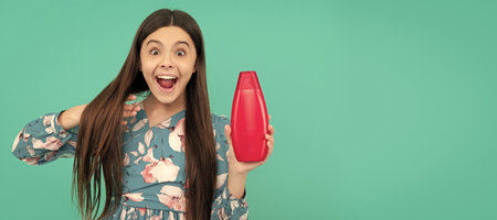surprised teen girl with long hair hold shampoo bottle, keratin. Banner of child girl hair care, studio poster header with copy space.の写真素材