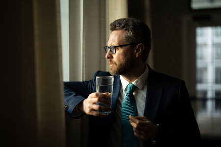 Stressed business man having headache at office. Tired businessman is working overtime and has headache. Man taking a Medicine pill from headache migraine.の写真素材