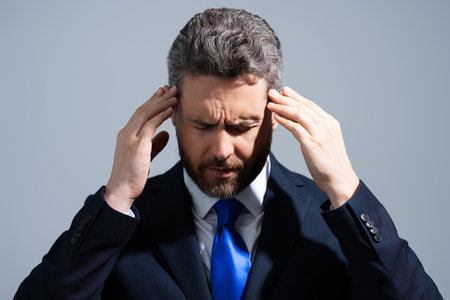 Headache, tiredness and stress. Business man in suit is tired got headache migraine. Headache pain concept. Painful men are stressed. Stressful and headache.の写真素材