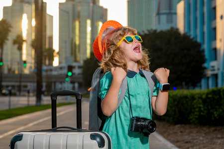Portrait of happy child traveler with luggage. Positive little tourist with suitcase ready to travelling. Happy kid tourist with baggage going to travel on holidays.の写真素材
