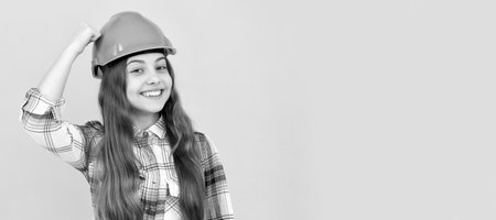 Engineer teenager girl. happy teen girl in helmet and checkered shirt, safety. Child in hard hat horizontal poster design. Banner header, copy space.の写真素材