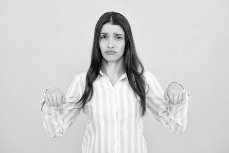Woman point at copy space, showing copyspace pointing down. Promo, girl showing advertisement content gesture, pointing with hand recommend product. Isolated background.の写真素材