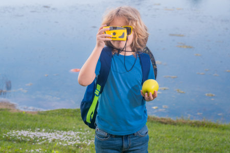 Child tourists with backpacks. Adventure, travel, and tourism concept. Kid walking with backpacks and camera on nature. Little explorer on trip.の写真素材