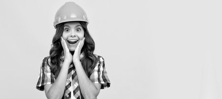 surprised teen girl with curly hair in construction helmet, carpenter. Child builder in helmet horizontal poster design. Banner header, copy space.の写真素材