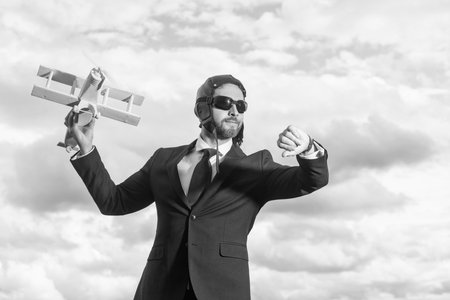 businessman in suit and pilot hat launch plane toy. check timeの写真素材