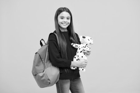 School girl hold toy. School children with favorite toys on yellow isolated background. Childhood...