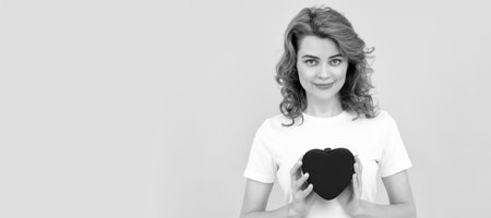 smiling redhead woman hold love heart on yellow background, 14 february. Woman isolated face portrait, banner with copy space.の写真素材