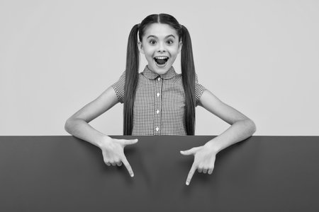 Teenage girl holds a blank for notification informing. Advertisement and sale. Markets and shops sales concept, blank board for copy space. Happy positive and smiling emotions of teen girl.の写真素材
