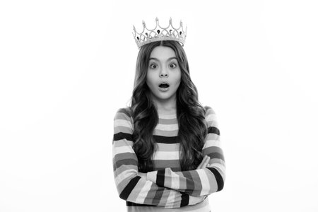 Little queen wearing golden crown. Teenage girl princess holding crown tiara. Prom party, childhood concept. Surprised face, surprise emotions of teenager girl.の写真素材