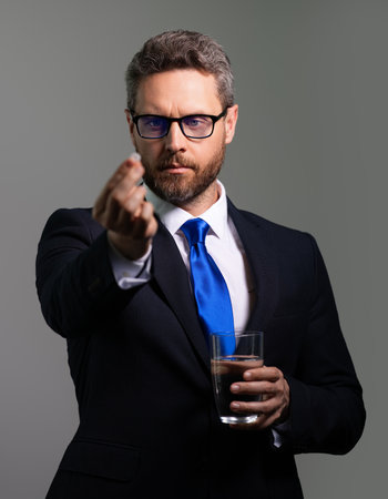 Head pain medicines pills concept. Cephalalgia and migraine. Man with sinus headache, tension or cluster headache on gray studio. Man taking a medicine pill from headache migraine.の写真素材