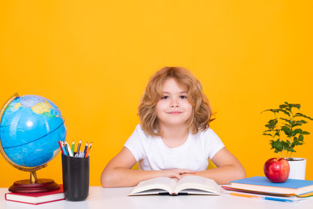 School kid reading book. School and education concept. Portrait of cute child school boy, isolated on yellow background. Back to school.の写真素材