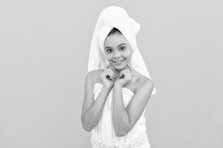 positive teen girl in shower towel with cream on faceの写真素材