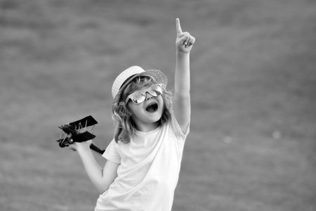 Childhood on countryside. Child pilot aviator with with paper wings or toy airplane dreams of traveling in summer in nature.の写真素材