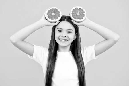 Happy teenager girl in t-shirt hold grapefruit orange, kids fruits vitamin.の写真素材