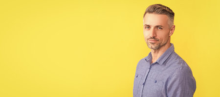 Man face portrait, banner with copy space. smiling mature man with graying hairstyle on yellow background, hairdresser.の写真素材