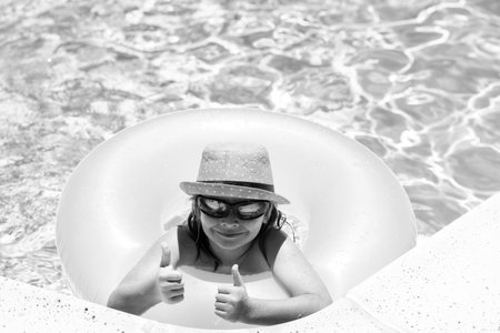 Child swim on ring floating in blue swimming pool. Inflatable ring, rest kids concept.の写真素材