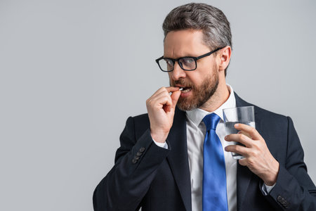 Head pain medicines pills concept. Cephalalgia and migraine. Man with sinus headache, tension or cluster headache on gray studio. Migraine symptoms. Chronic headaches. Headache triggers.の写真素材