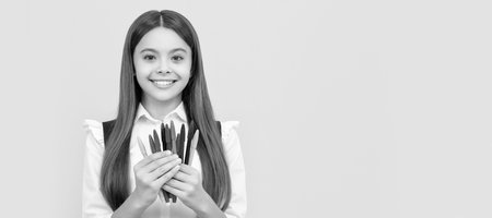 Happy girl child hold felt-tip pens yellow background, school tip. Banner of schoolgirl student. School child pupil portrait with copy space.の写真素材