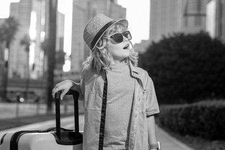 Child with travel suitcase on vacation. Kids travel and adventure concept. Child boy going on vacation holding luggage travel bag outdoor.の写真素材