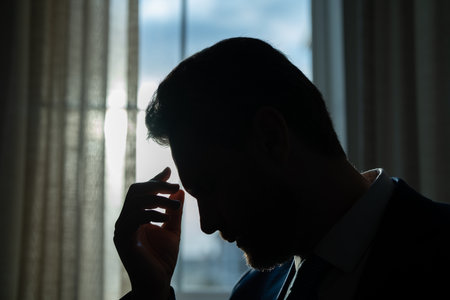 Tired man feel pain holding glasses rubbing dry irritated eyes fatigued from computer work, stressed man suffer from headache bad vision sight problem sit at office. Deadline and stressed job.の写真素材