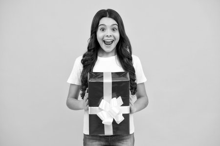 Amazed teenager. Emotional teenager child hold gift on birthday. Funny kid girl holding gift boxes celebrating happy New Year or Christmas. Excited teen girl.の写真素材