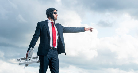 businessman in suit and pilot hat launch plane toy on sky background. think bigの写真素材