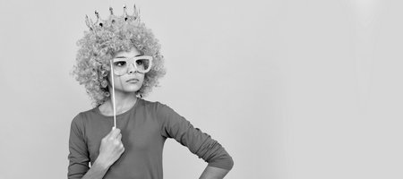 serious teen girl in fancy clown wig wear queen crown and funny party glasses, arrogant. Funny teenager child in wig, party poster. Banner header, copy space.の写真素材
