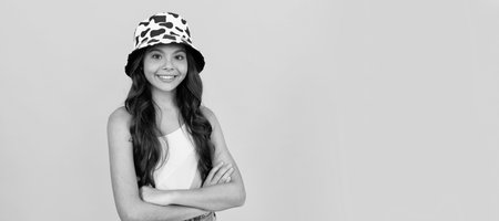 happy teen girl in summer bucket hat has curly hair on yellow background, fashion accessory. Child face, horizontal poster, teenager girl isolated portrait, banner with copy space.の写真素材
