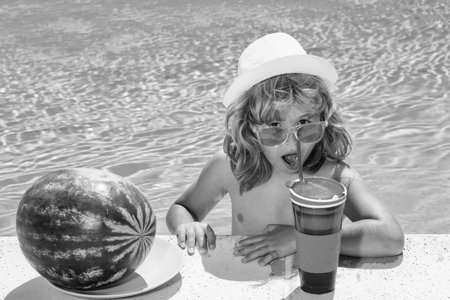 Funny kid in swimming pool. Child drink cocktail, summer fruits, watermelon. Summer cocktail for children.の写真素材
