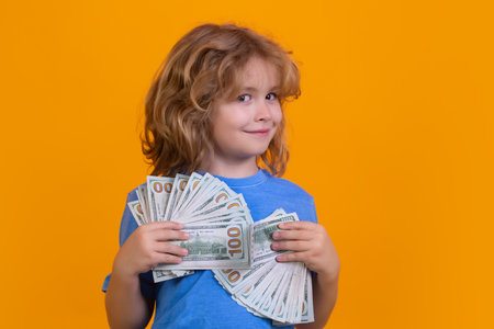 Child having a lot of hundred dollars isolated on yellow background.の写真素材