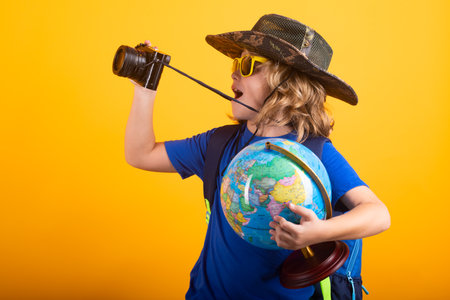 Child with backpack and camera, explorer. Concept of exploration and discovery. Kid hold world...